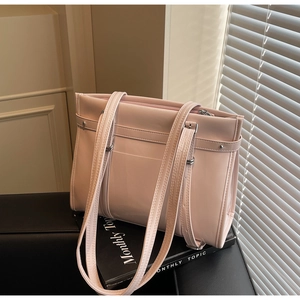 Close-up of pink glossy tote bag with silver rivets placed on a fashion magazine