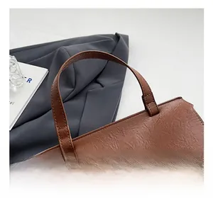 Dettaglio borsa marrone con trama in pelle litchi e chiusura in metallo vintage