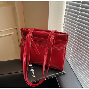 Close-up of red glossy leather tote bag with functional zipper pocket and long handles