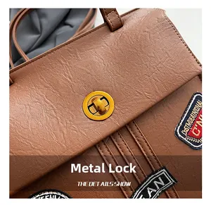 Dettaglio della borsa vintage in pelle marrone con chiusura a rotazione dorata e toppa