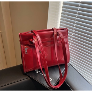 Detail of red glossy patent leather tote bag featuring functional multiple zipper pockets