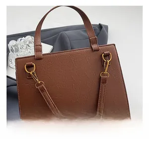 Dettaglio dei ganci in metallo dorato e della pelle marrone di questa borsa tote