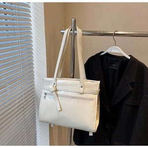 Detail of cream white faux leather tote bag with silver zipper pocket and decorative knots