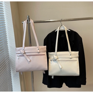 Detail of pink and off-white PU leather tote bags featuring decorative knotted belt accents