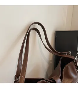 Détail des doubles bandoulières réglables avec boucles métalliques sur un sac en cuir