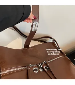 Détail de la boucle métallique argentée et du fermoir sur le sac bandoulière en similicuir marron