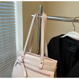 Detail of soft pink faux leather tote bag with double straps in professional office setting