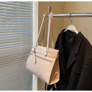 Detail of elegant beige leather tote bag with stylish belt knot and front zipper pocket
