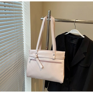 Detail view of pink leather tote bag with zip pocket and bow hanging on a metal rack