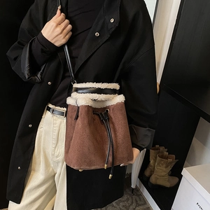 Brown suede bucket bag with white faux fur trim and black leather drawstring shoulder strap
