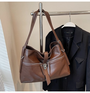 Sac fourre-tout marron foncé en similicuir avec boucles argentées devant un costume noir