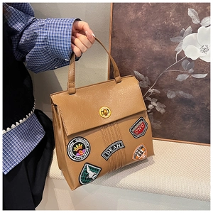Dettaglio borsa tote vintage marrone con toppe ricamate e chiusura a girello oro