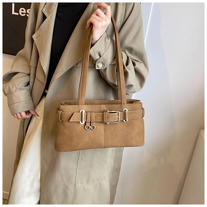 Detailed close-up of brown matte leather shoulder bag with decorative buckle and stitching