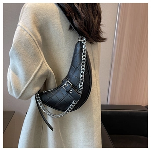 Détail du sac croissant noir en similicuir crocodile avec chaîne argentée sur un mannequin