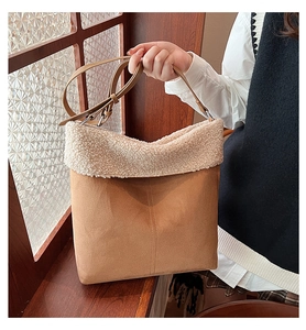 Detail of brown suede tote bag with plush white faux shearling trim and adjustable strap