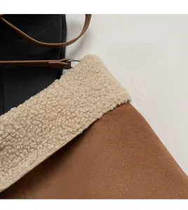 Detailed close-up of brown suede bag with white faux fur trim and fine stitching