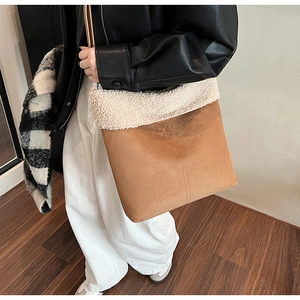Detail view of brown suede shoulder bag with white faux fur trim on a model