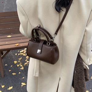 Deep brown textured leather crossbody bag styled with a cream winter wool coat