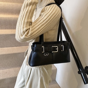 Retro black leather baguette shoulder bag with buckle detail worn by a model