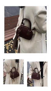 Detail of dark brown frosted leather bowling bag showing handles and gold bell charm