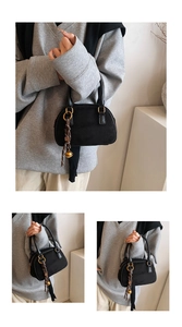 Detail view of black suede mini bag with gold ring hardware and decorative lanyard cord