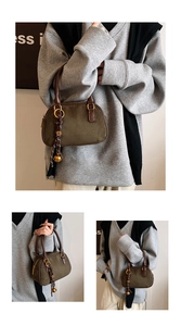 Detail of olive green suede Boston bag with leather handles and unique decorative charms