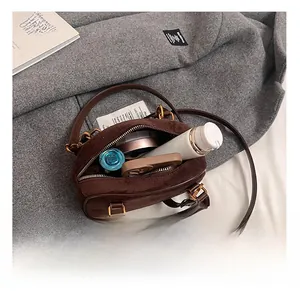 Interior view of brown suede bowling bag showing daily essentials and golden hardware