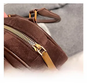 Detail view of the polished gold zipper and hardware on dark brown suede handbag