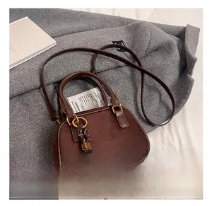 Close-up of retro brown crossbody bag with suede patchwork and woven cord detail