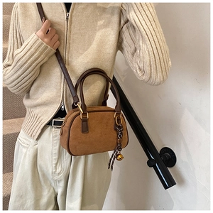 Brown frosted Boston handbag with shoulder strap worn by a model on stairs