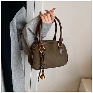 Detail of olive green matte suede handbag with leather handles and gold bell charm