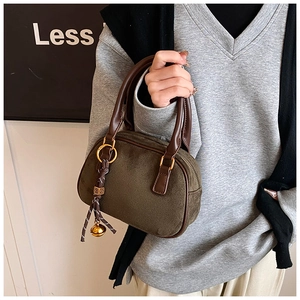 Detail of dark olive suede bowling bag with leather handles and gold bell charm