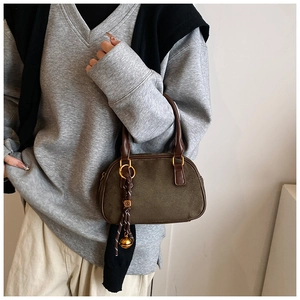 Detailed macro view of dark coffee matte handbag with golden hardware and bell charm