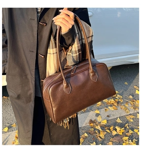 Detail of deep brown leather tote bag with long handles and metallic top zipper
