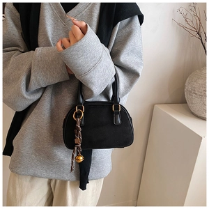 Detailed macro view of black matte suede mini bag with gold hardware and charm
