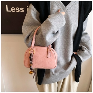 Close-up of pink matte texture handbag with silk scarf and gold bell accessory