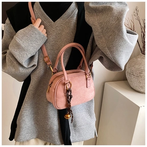 Pink matte mini handbag detail with woven knot and golden bell charm accessory