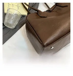 Close-up of brown lychee grain leather tote bag with silver metal bottom feet studs
