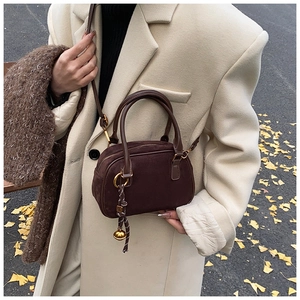 Brown matte suede crossbody bag styled with beige autumn coat on ginkgo leaf background