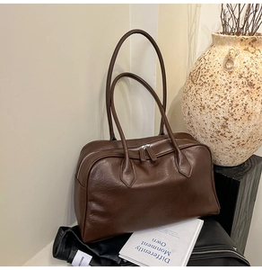 Detail of dark brown vintage handbag with double zippers and textured leather finish