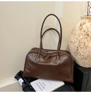 Close-up of a retro brown oil wax leather tote bag featuring silver zipper and side pocket