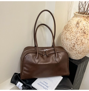 Close-up of retro dark brown leather boston bag with long handles and double zippers