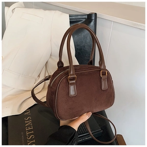 Close-up of a matte dark brown Boston handbag with golden metal hardware and strap