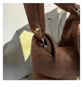 Detailed close-up of golden hardware and stitching on a brown suede shoulder tote bag