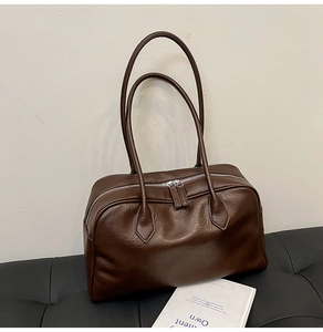 Close-up of retro brown leather tote bag with silver double zippers and texture detail