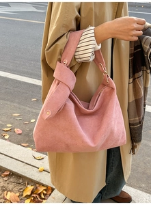 Pink suede underarm bag detail showing knotted handle and gold metal rivet accents