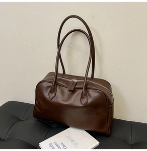 Detail of dark brown vintage Boston tote bag with oily leather texture and double zippers
