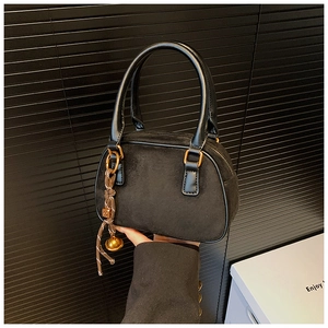 Detail of black matte saddle handbag with braided rope and golden bell pendant
