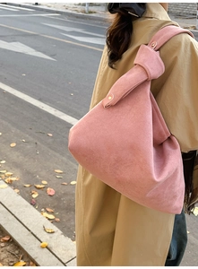 Close-up of pink frosted shoulder bag featuring a unique knotted handle design