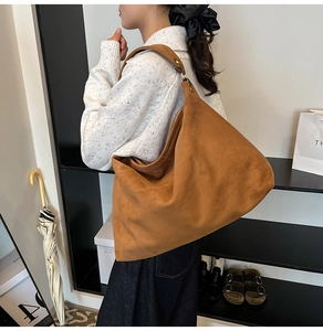 Detailed texture of large brown suede hobo bag shown on a model's shoulder